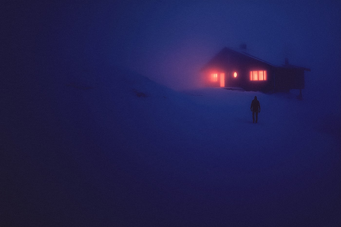 A mysterious figure walking towards a lonely, warmly lit hut in the snowy mountains in the darkness of the night. | Wall Art