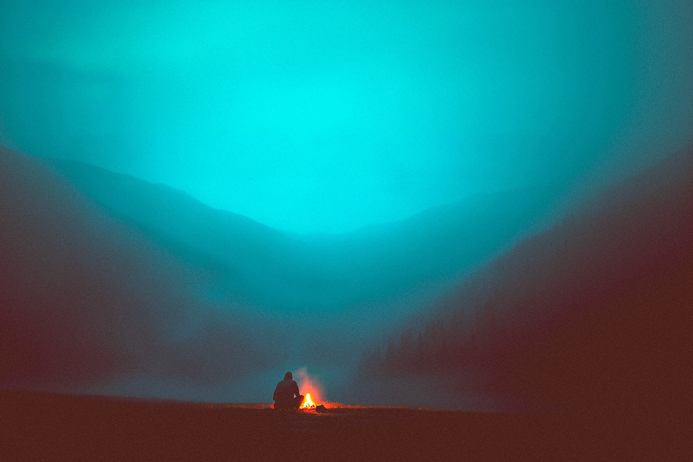 A person sitting all alone at a campfire in the mountains. The crackling fire brings some warmth into the vast, cold landscape. | Wall Art