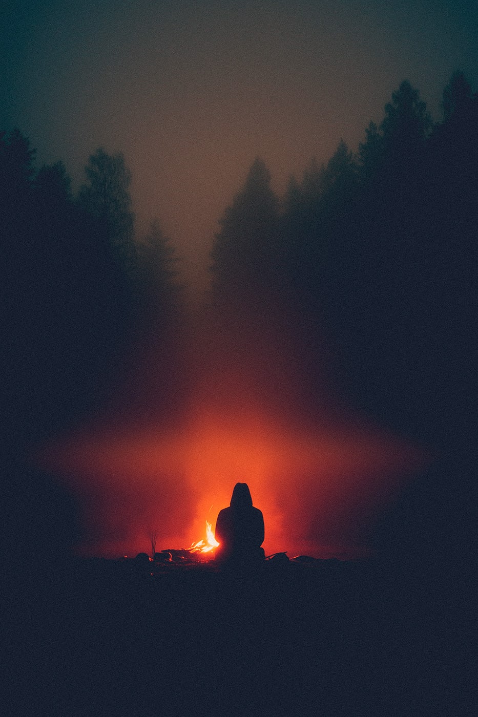 A hooded person sitting at a cozy campfire at night in a dark forest alone by himself. | Wall Art